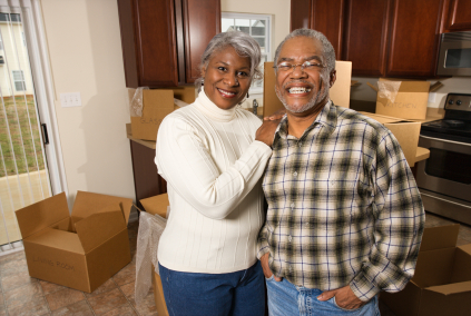 Portrait of middle-aged African-American couple in kitchen with moving boxes.